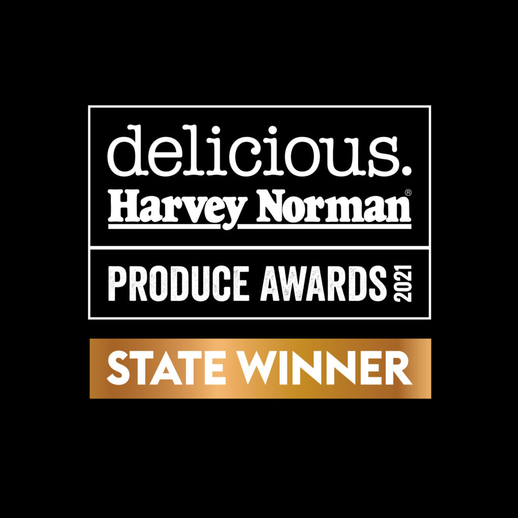 A black square with white and gold metallic writing reads: Delicious and Harvey Norman Produce Awards 2021 - State Winner