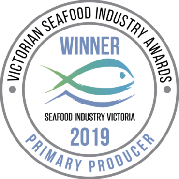 A round logo for the Victorian Seafood Industry Awards - 2019 Primary Producer Winner, with a blue and green fish in the middle.