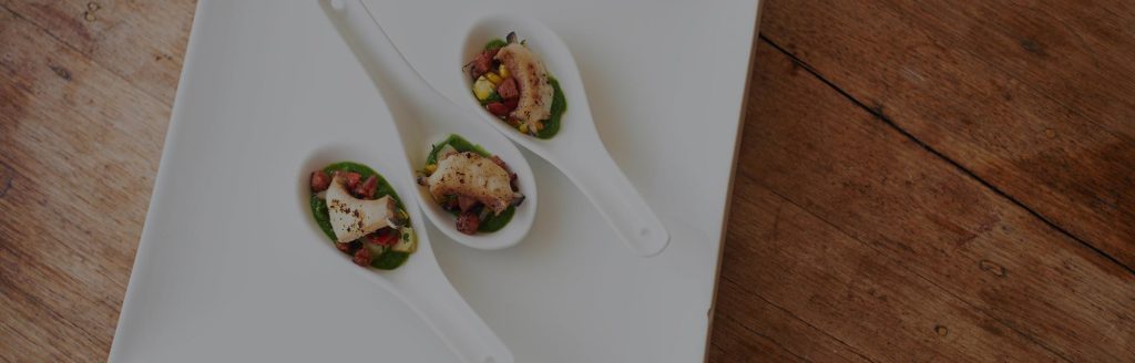 Three large serving spoons are filled with abalone with chorizo corn salsa and rocket sauce.