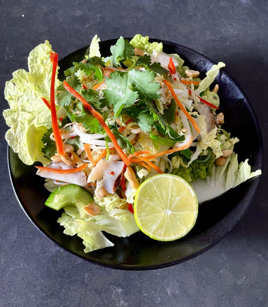 Yumbah Aquavide Abalone Asian Noodle Salad served in a black bowl, with half a lime sitting on top.